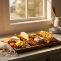 Walnut serving board loaded with artisan cheeses, dried fruit, and crackers in a warm kitchen setting